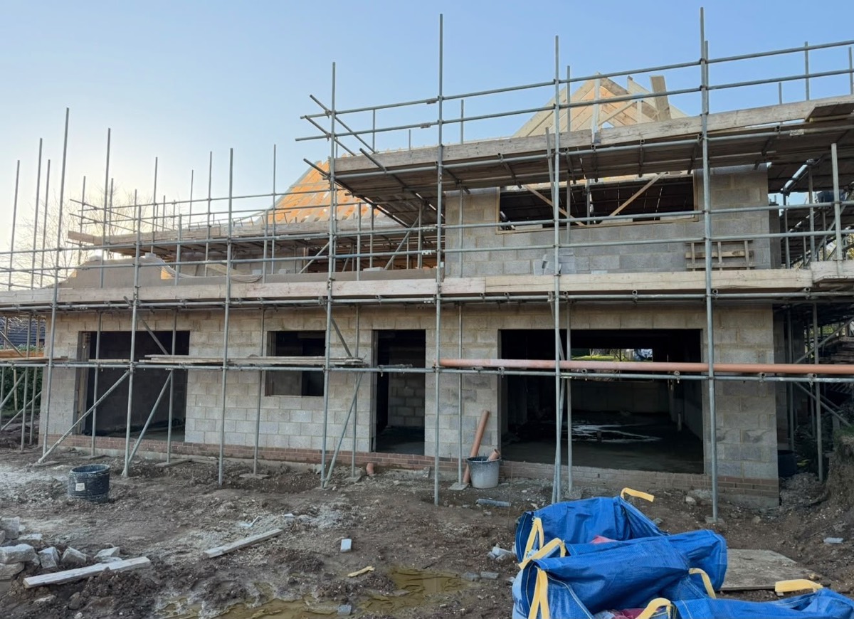 Scaffolded blockwork elevation with roof trusses going on