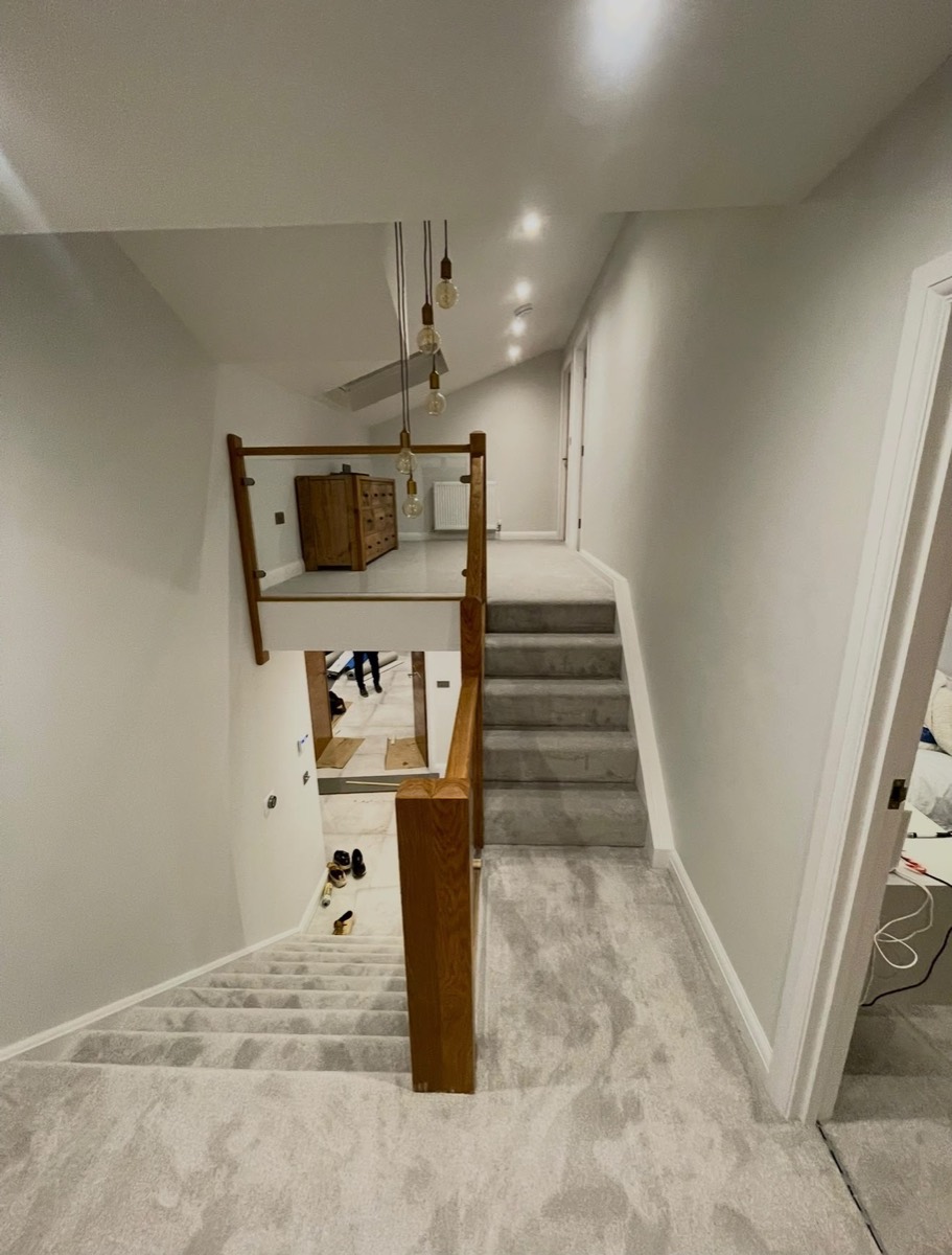 Staircase landing with glass balustrade and filament pendant lights