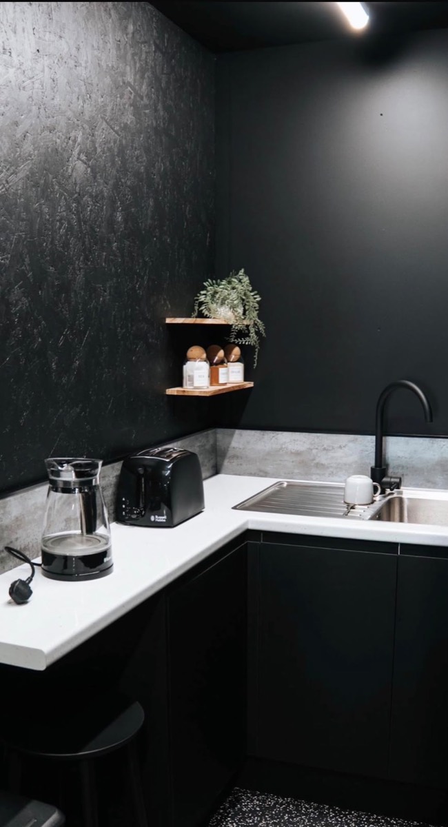 Kitchenette with black cabinets and white worktop